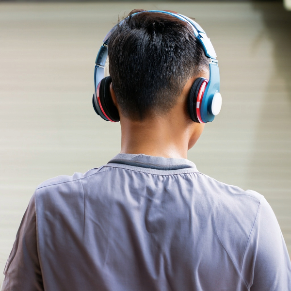 Back shot of a young boy wearing blue headphones.